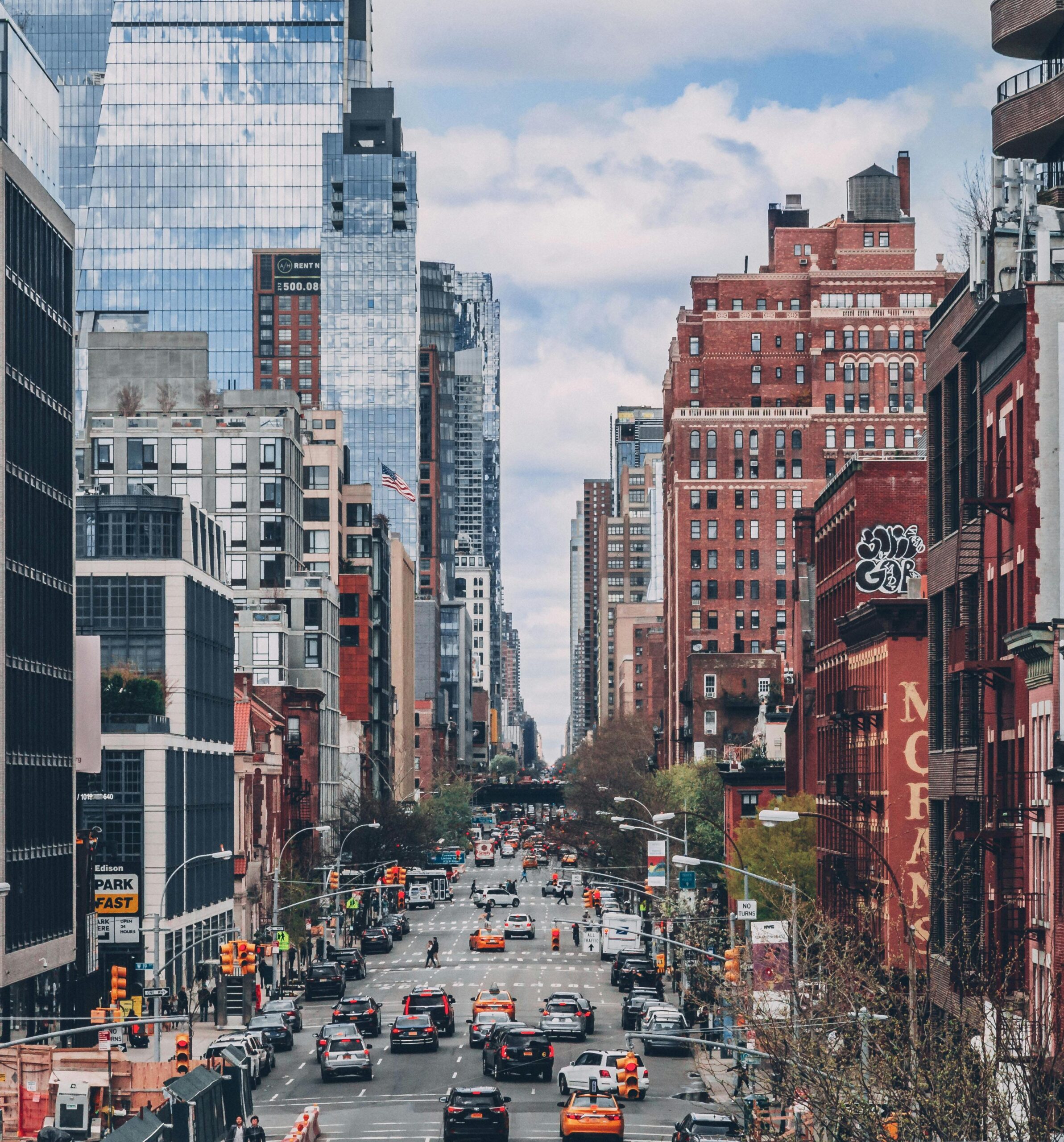 Bustling street scene in NYC with iconic skyscrapers and busy traffic.