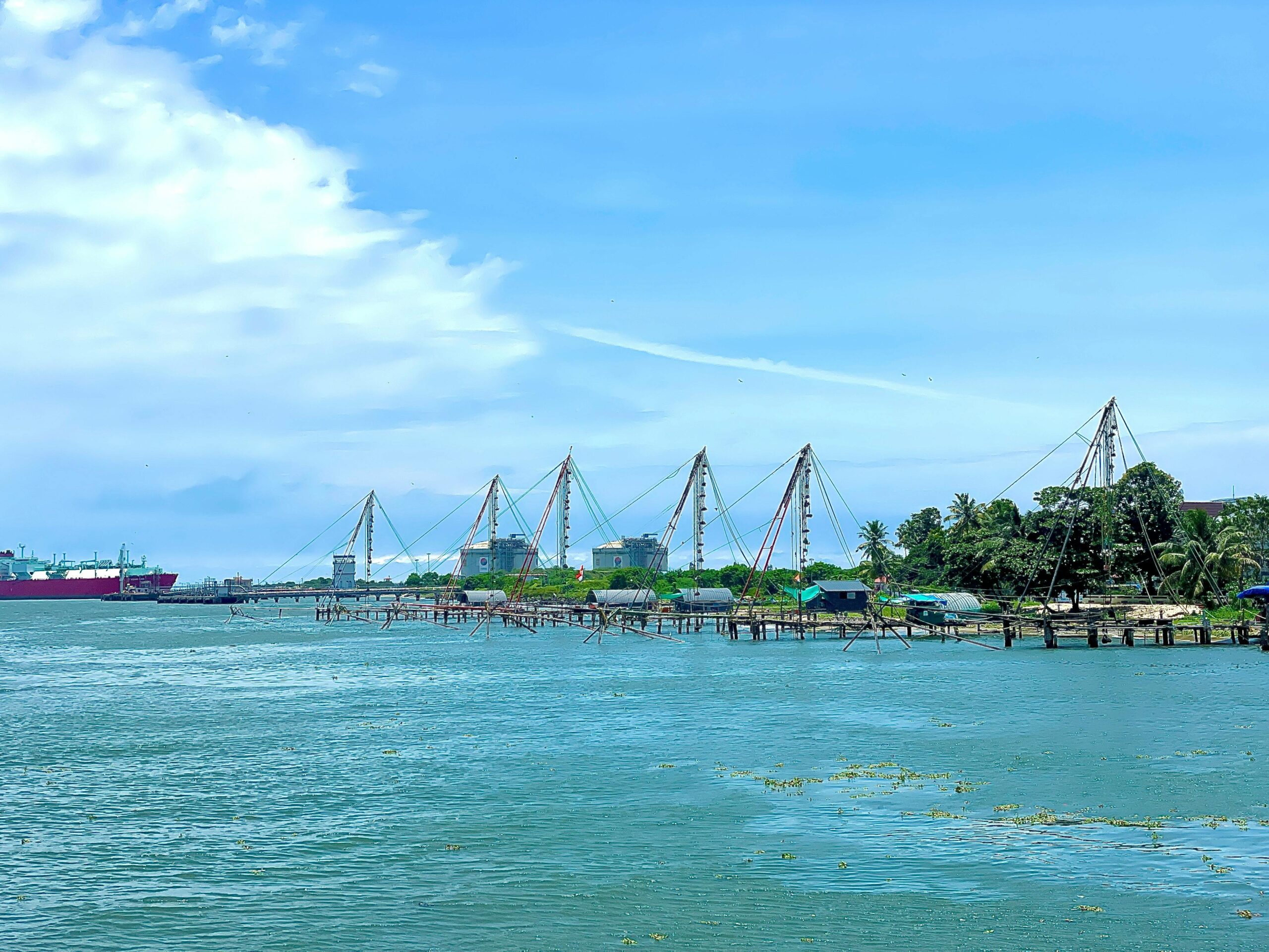 Traditional Chinese fishing nets line the waterfront in Cochin, India on a bright summer day.